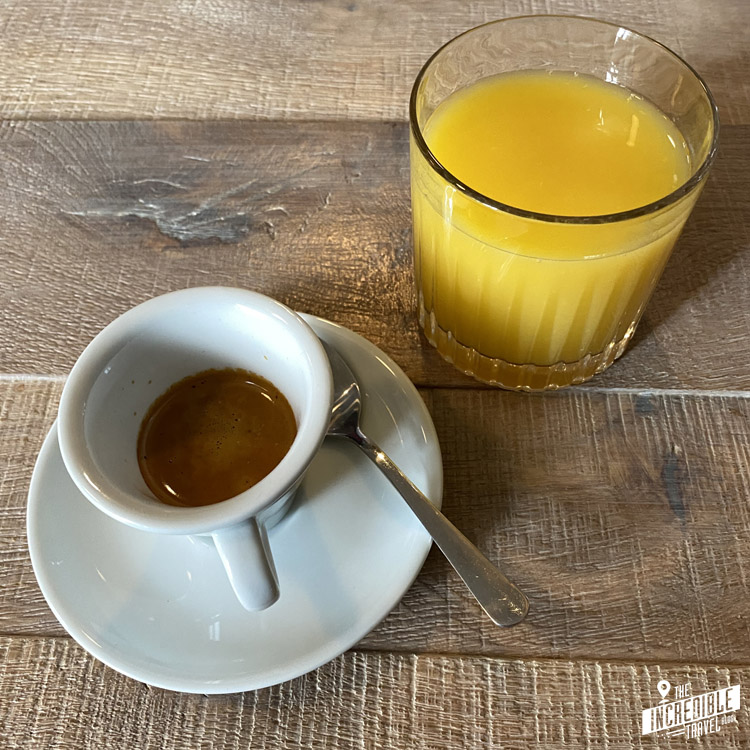 Espresso in einer Tasse und Orangensaft im Glas auf Holztisch