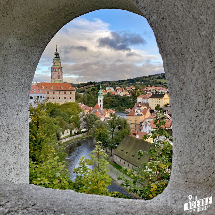 Blick durch ein Mauerfenster auf Teile der Altstadt und den Schlossturm von Český Krumlov