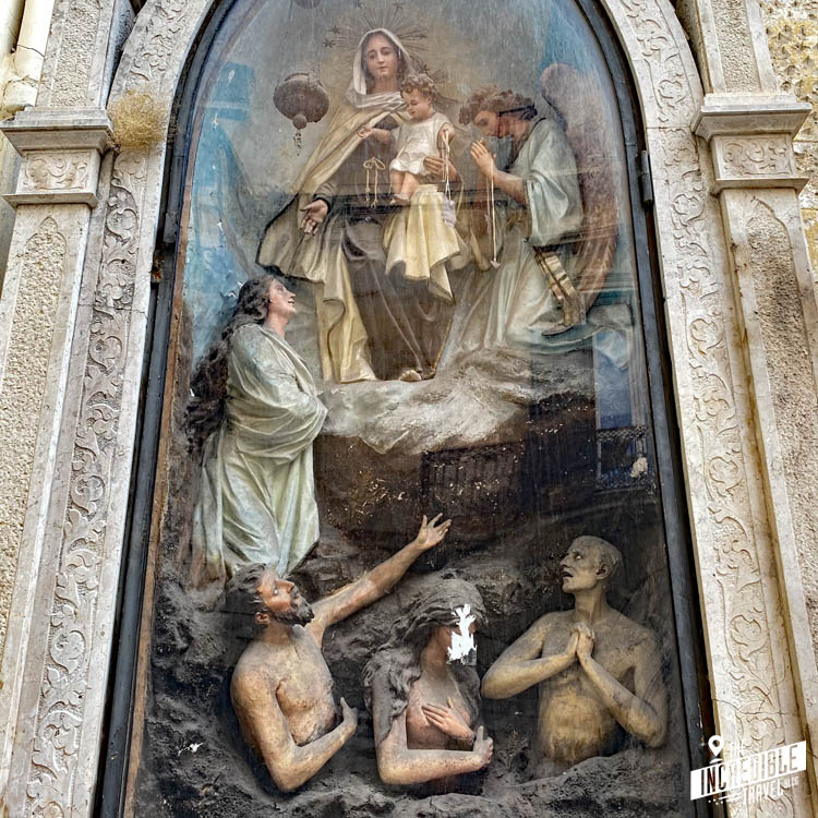 Marienstatue mit Jesus und weiteren Figuren hinter Glas