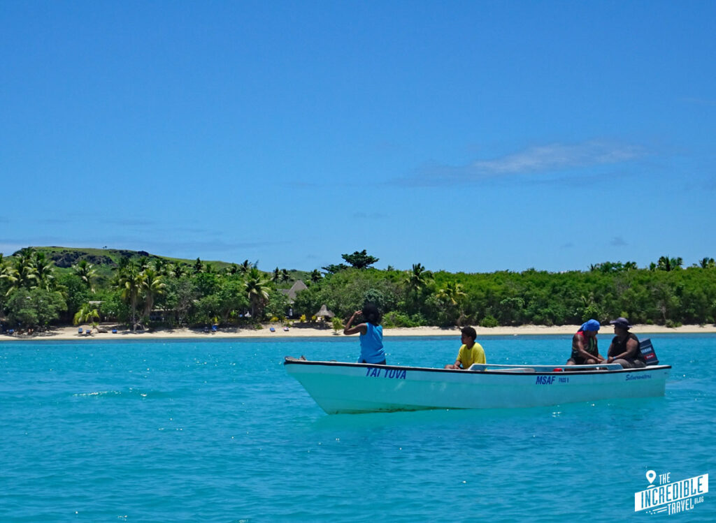 Kleines Motorboot vor Südseeinsel mit blauem Wasser