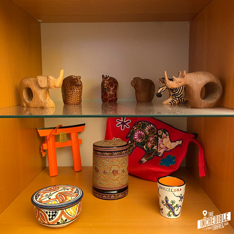 Blick in ein Regal mit Holztieren, einem japanischen Tor und verschiedenen anderen Gegenständen