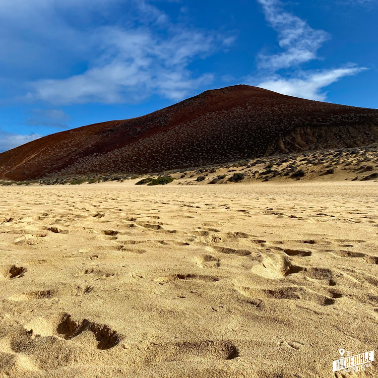 Blick über viel Sand auf einen Berg an der Playa de las Conchas