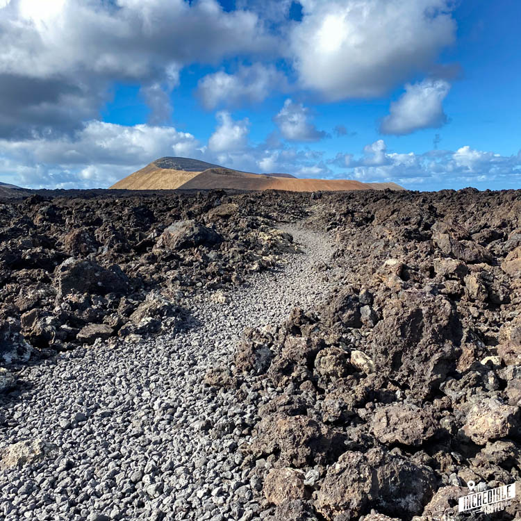 Weg durch Lavabrocken zu einem Vulkankrater