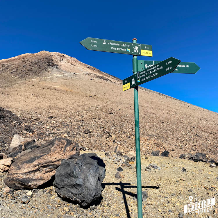 Hinweisschilder für verschiedene Wanderwege, im Hintergrund der Berggipfel