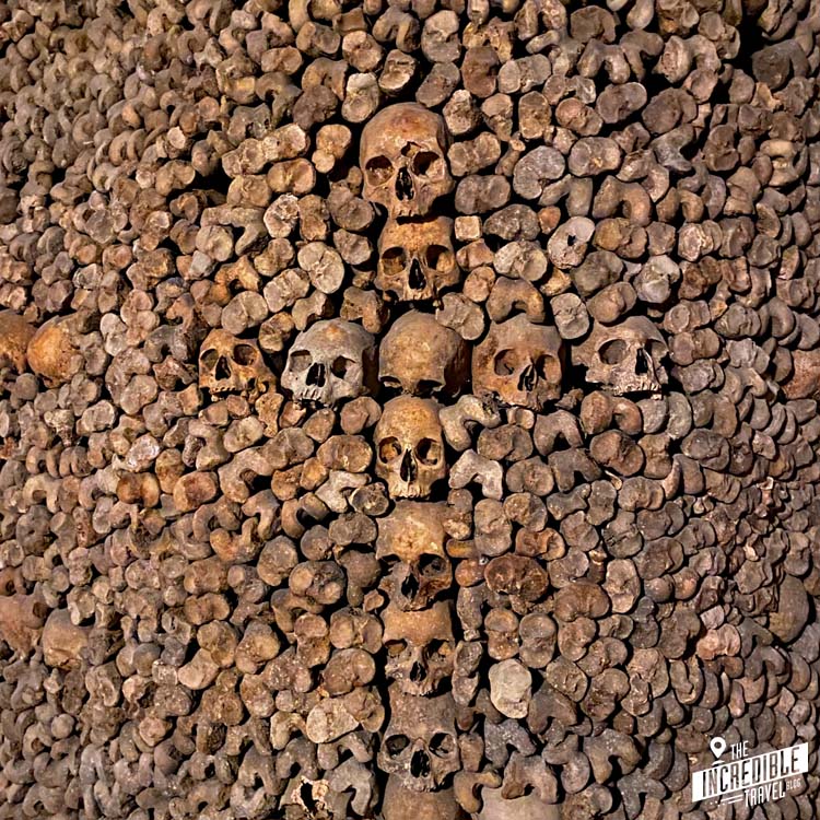 Kreuz aus Schädeln in einer Wand aus Knochen