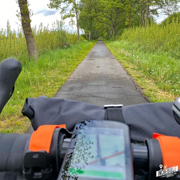 Blick über Lenker und Fahrrad-Navigationssystem auf einen Radweg