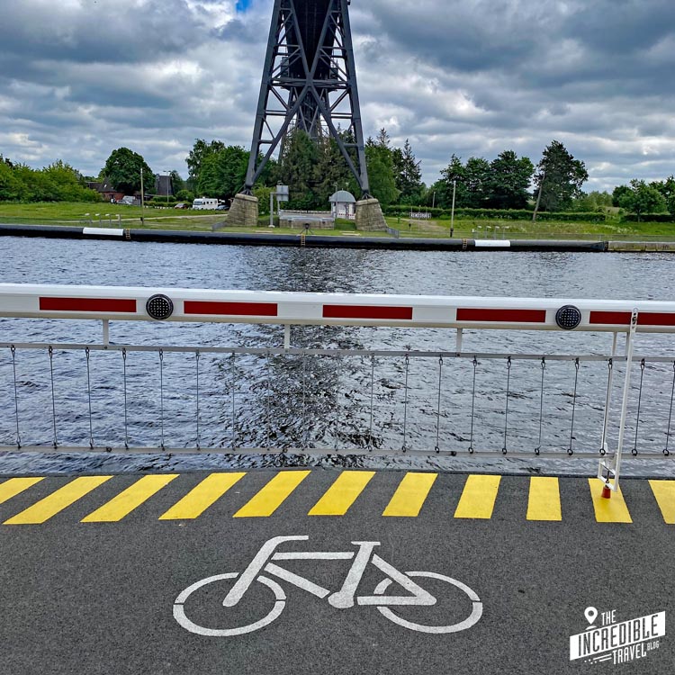 Fahrradsymbol auf dem Boden der Fähre, im Hintergrund das andere Ufer des Nord-Ostsee-Kanals