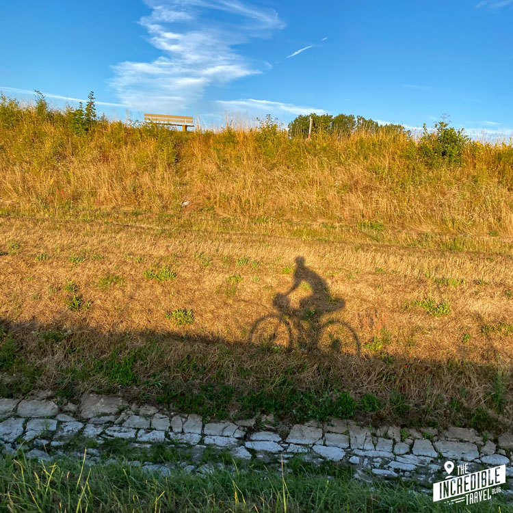 Foto des eigenen Schattens mit Fahrrad während der Fahrt in der Morgensonne