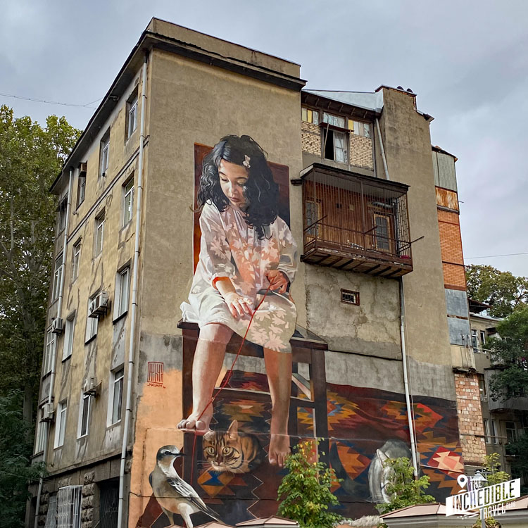 Riesengroßes Gemälde eines Mädchens mit Katze an einer Hauswand