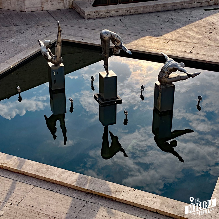 Klippenspringerstatuen und ihre Spiegelungen über einer Wasserfläche
