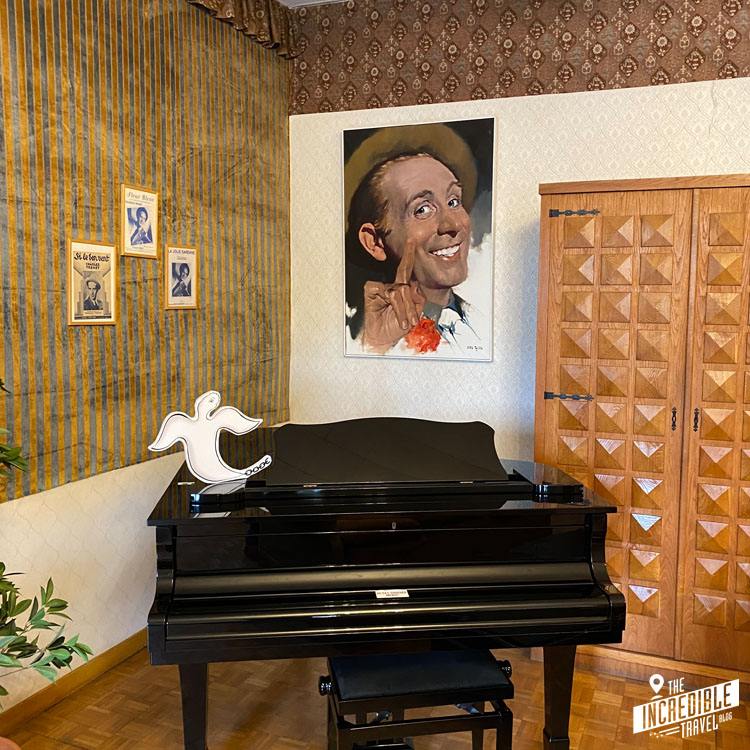 Schwarzes Klavier und Gemälde von Charles Trenet an der Wand