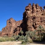 Panoramaaufnahme im Wadi Disah mit Jeep und Palmen vor Sandsteinwänden