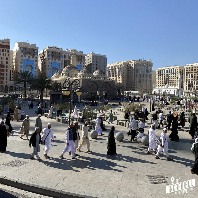 Jede Menge Menschen auf einem Platz mit Moschee im Hintergrund