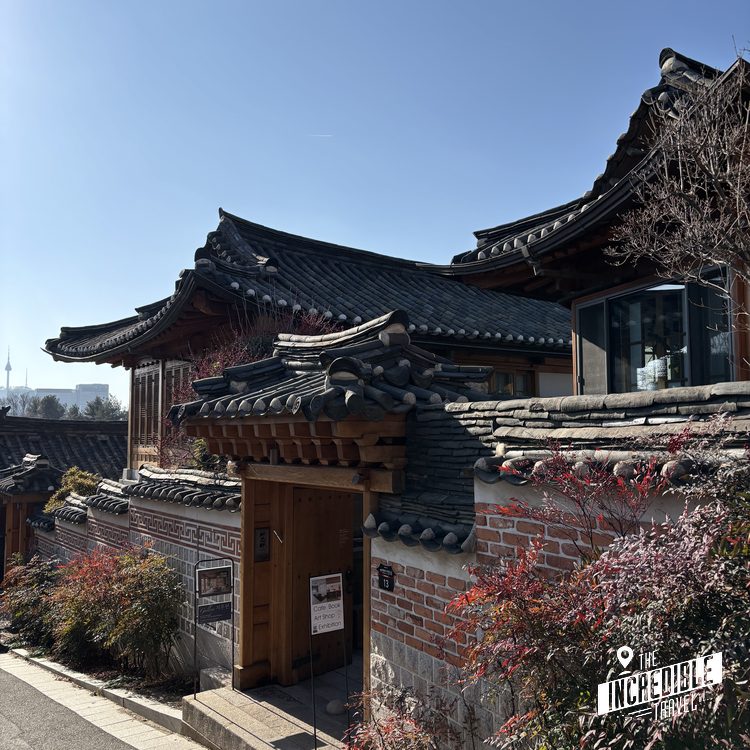 Traditionelles Gebäude mit geschwungenen schwarzen Dächern, roten Ziegeln und verziertem Eingang unter blauem Himmel