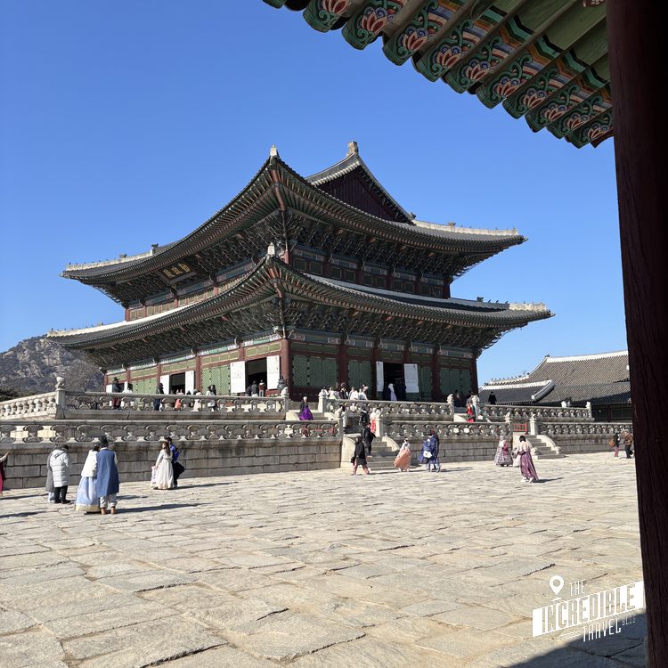 Traditionelle ostasiatische Pagode mit mehreren Dächern und verziertem Dachgesims, davor großer Platz mit Besuchern in historischen Gewändern.