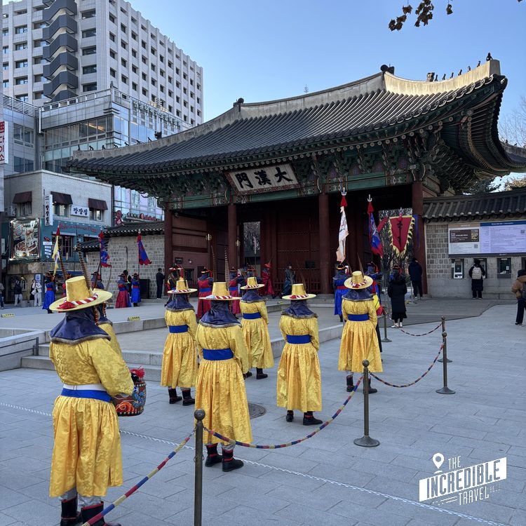 Traditionelle Zeremonie mit Personen in gelben Gewändern vor einem asiatischen Tempel mit geschwungenem Dach