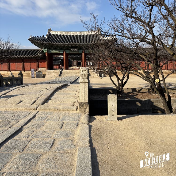 Traditionelle asiatische Tempelanlage mit gelben Dachziegeln, roten Mauern und kahlen Bäumen im Innenhof