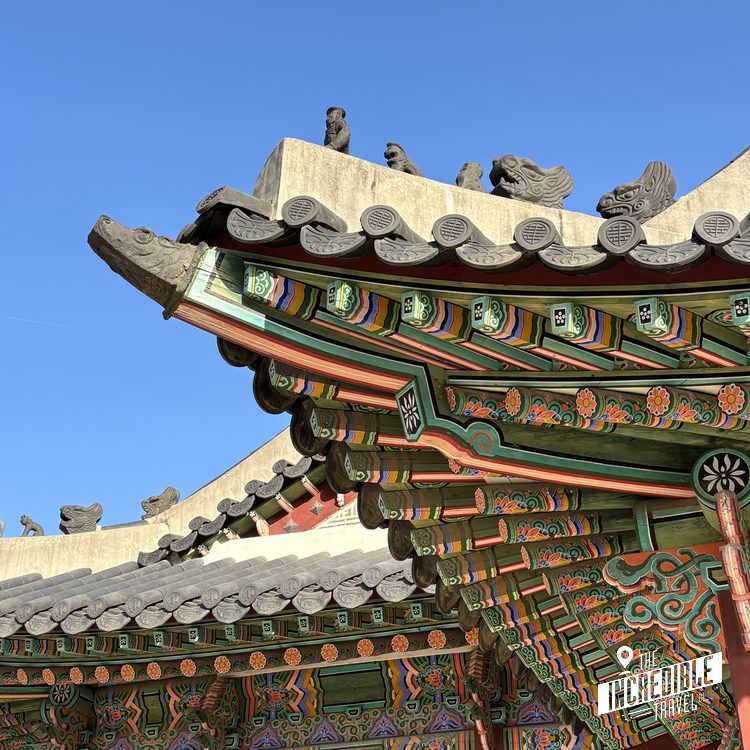 Traditionelle asiatische Dachziegel mit aufwendigen Verzierungen und dekorativen Figuren gegen blauen Himmel