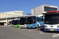 Parkplatz mit mehreren touristischen Bussen in verschiedenen Farben vor einem Gebäude mit koreanischer Beschriftung unter blauem Himmel.