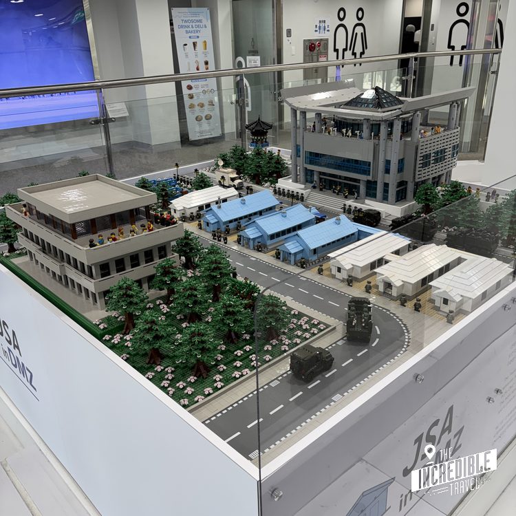 Architekturmodell einer urbanen Platzanlage mit Gebäuden, Grünflächen und temporären Strukturen in einer Ausstellung.