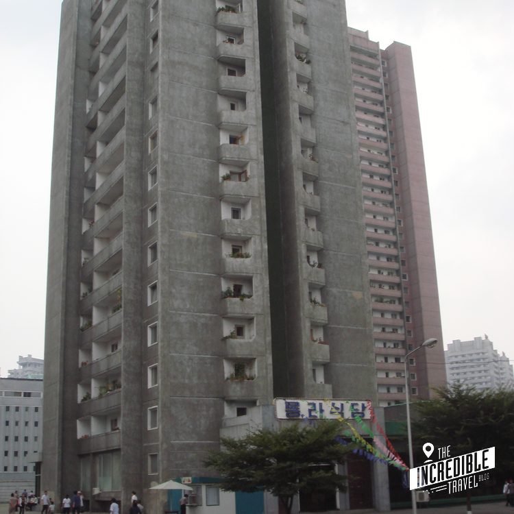 Mehrstöckiges Wohnhochhaus aus Beton mit asymmetrischer Architektur und koreanischen Schriftzeichen an der Fassade.