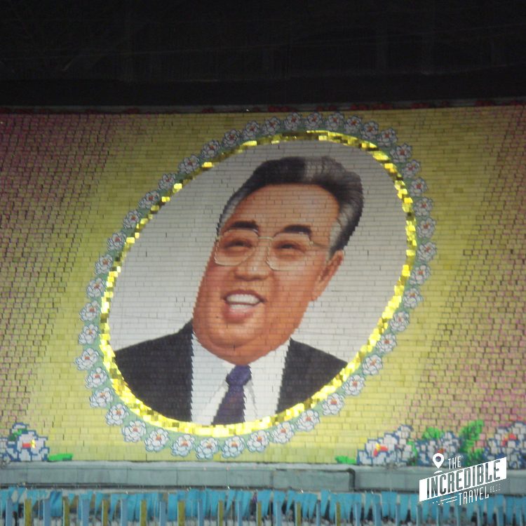 Großes Porträt von Kim Il Sung in gelbem Oval-Rahmen auf der Stadiontribüne